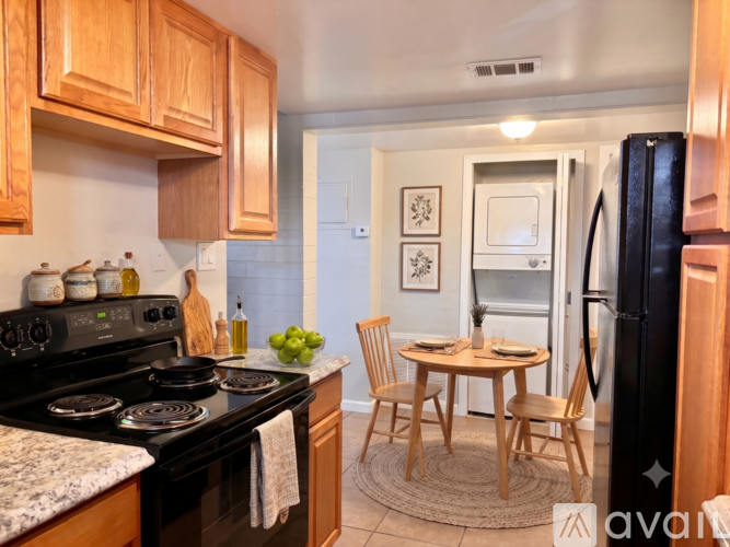 A kitchen with a black refrigerator, wooden cabinets, and a granite countertop.