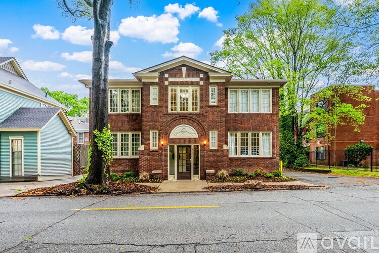 A red brick house with a tree in front.