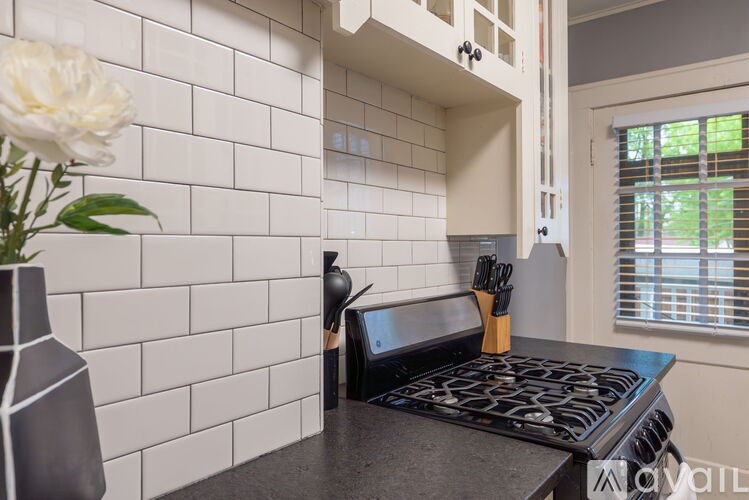 A kitchen with a white tile wall and a black stove top.