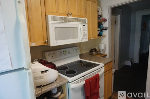 A kitchen with a white microwave above a stove and a white toaster on the counter.