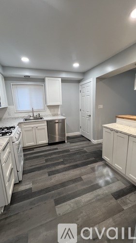 A kitchen with white cabinets and a grey floor.