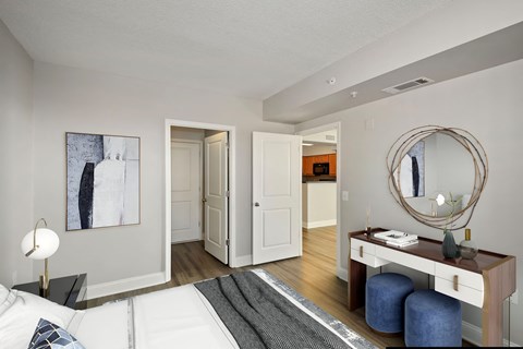 A modern bedroom with a large bed, a desk with a mirror, and a painting on the wall.