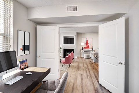 A room with a desk, chairs, and a television.