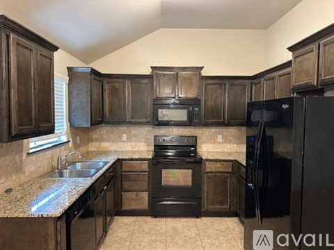 A kitchen with black appliances and wooden cabinets.