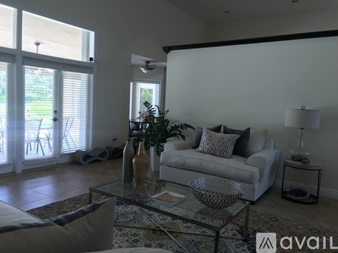 A living room with a glass coffee table and a white couch.