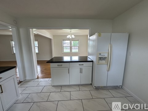 A kitchen with white cabinets and a black countertop.