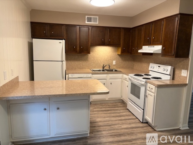 A kitchen with white appliances and brown cabinets.