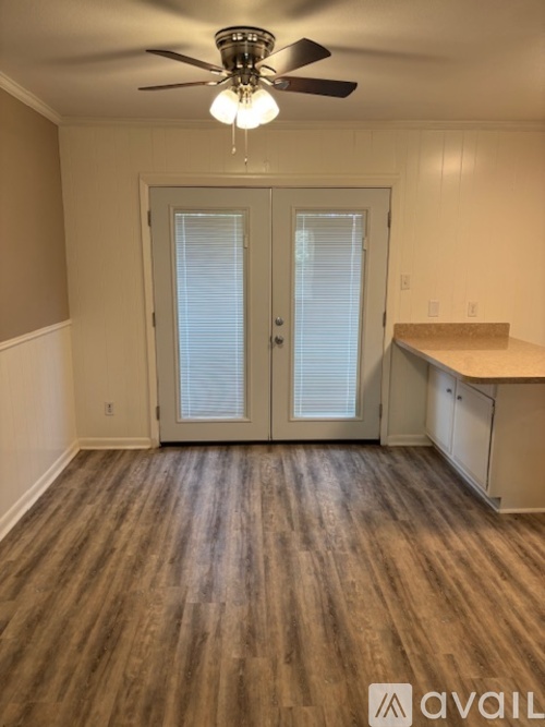 A room with a ceiling fan and wooden flooring.