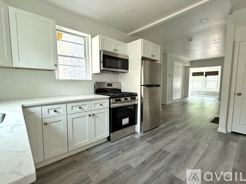 A kitchen with white cabinets and a grey floor.