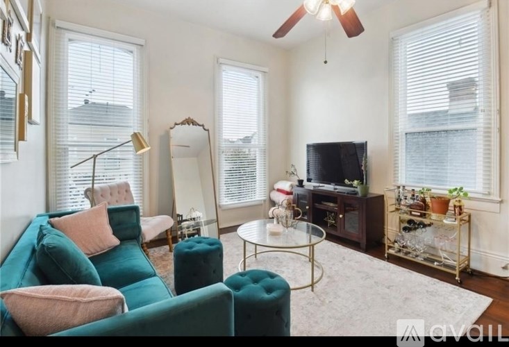 A living room with a green couch, a mirror, a television, and a glass table.