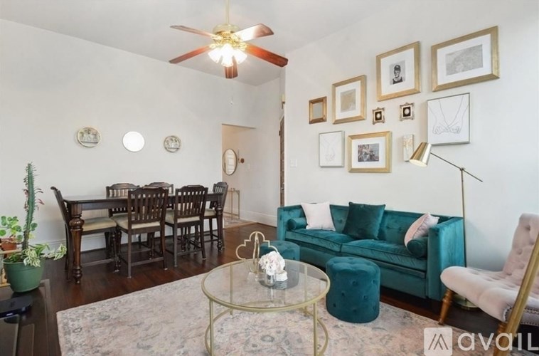 A living room with a green couch, a glass coffee table, and a ceiling fan.
