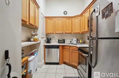 A kitchen with wooden cabinets and a stainless steel refrigerator.