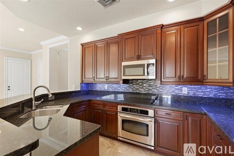 A kitchen with dark wood cabinets and a black granite countertop.