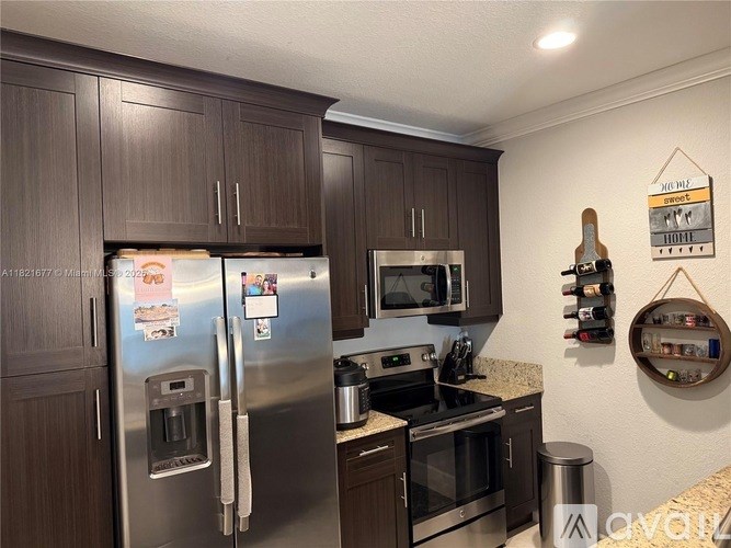 A kitchen with a refrigerator, microwave, oven, and a coffee maker.