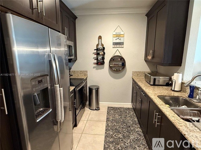 A kitchen with a stainless steel refrigerator and black cabinets.