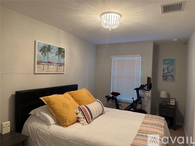 A bedroom with a bed, pillows, a nightstand, and a bicycle.