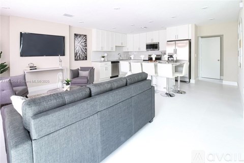 A modern living room with a grey sofa and a television on the wall.