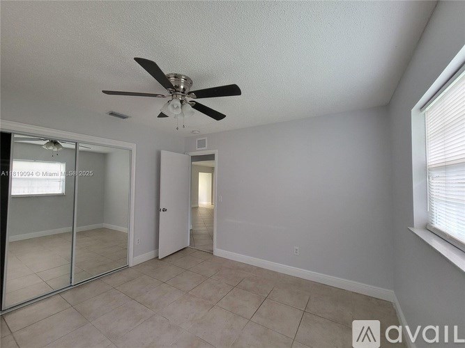 A spacious room with a ceiling fan and a sliding glass door.