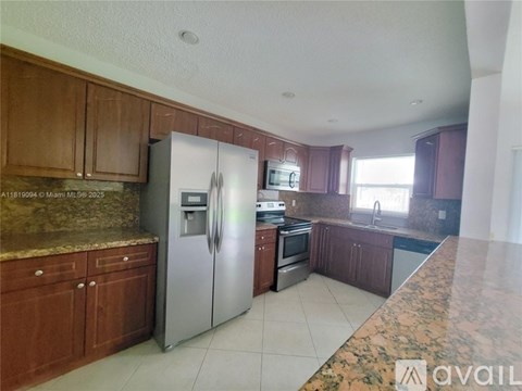 A kitchen with brown cabinets and a marble countertop.