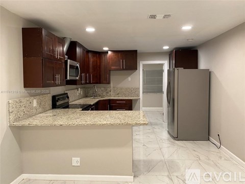 A kitchen with brown cabinets and a marble countertop.