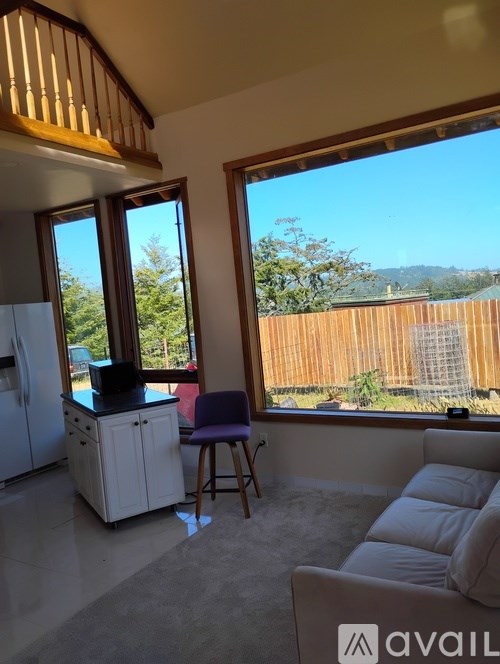 A kitchen with a refrigerator and a bar stool in front of a window.