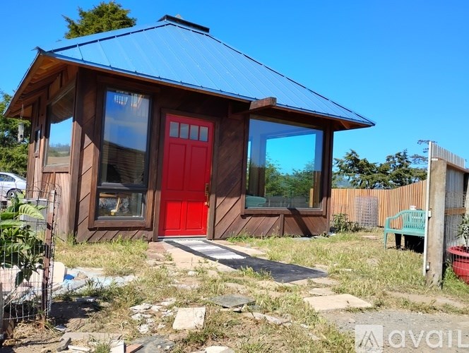A small wooden house with a red door and a blue roof.