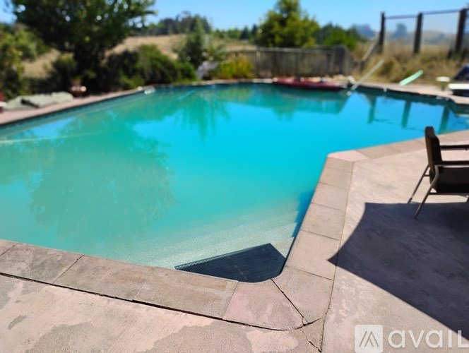 A swimming pool with a chair and a table nearby.