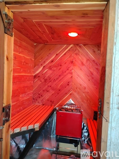 A small room with wooden walls and ceiling with a red light on.