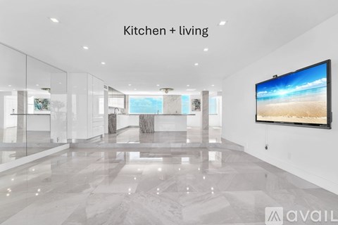 A modern kitchen and living room with a large marble floor and a flat screen TV mounted on the wall.