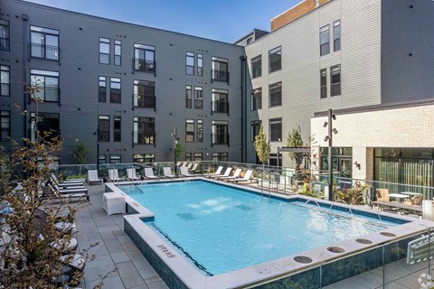 A small pool surrounded by chairs and buildings.