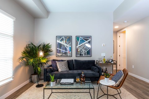A living room with a black couch and a glass coffee table.