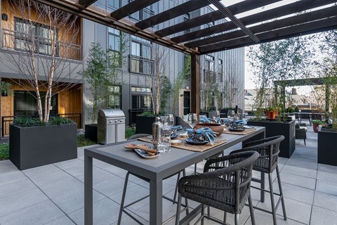 A modern outdoor dining area with a long table and chairs.