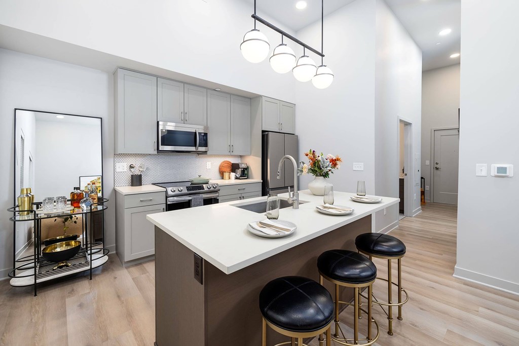 A modern kitchen with a white countertop and black bar stools.