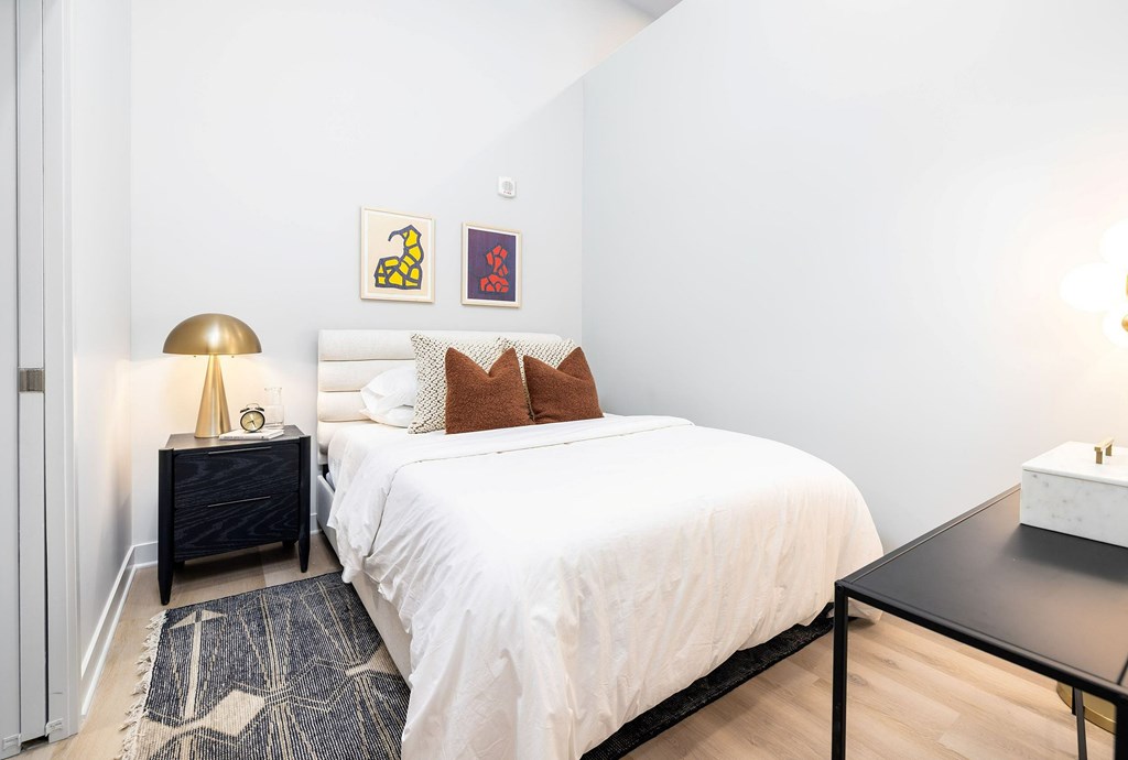 A bedroom with a white bed and a black side table.