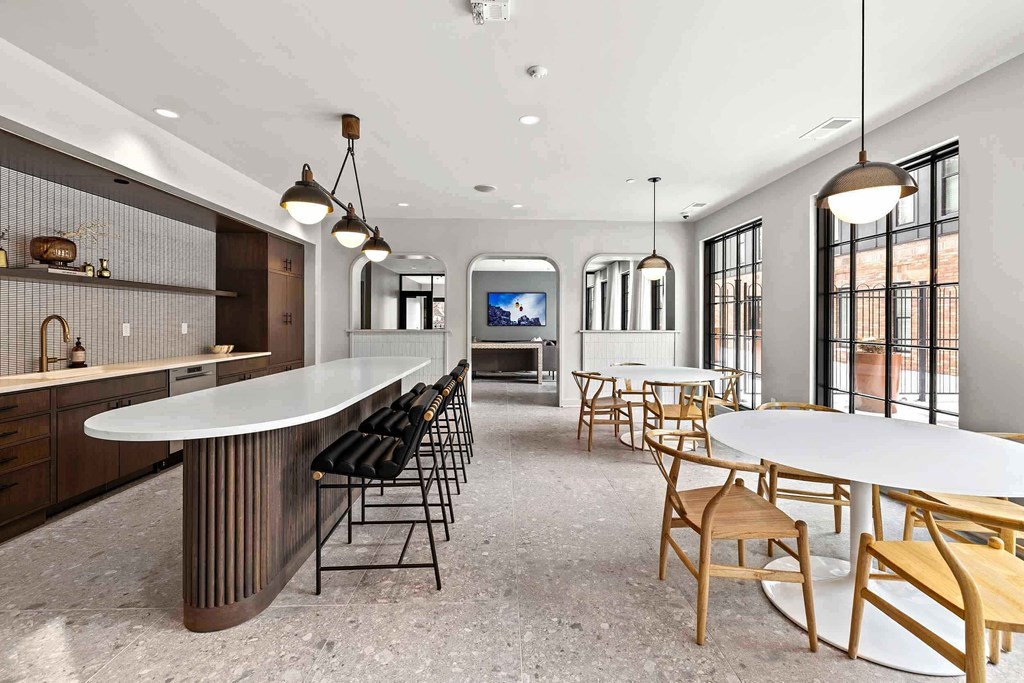 A modern kitchen with a long white island and wooden chairs.
