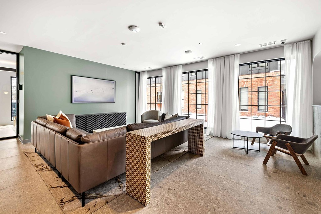 A living room with a brown couch, a coffee table, and a painting on the wall.