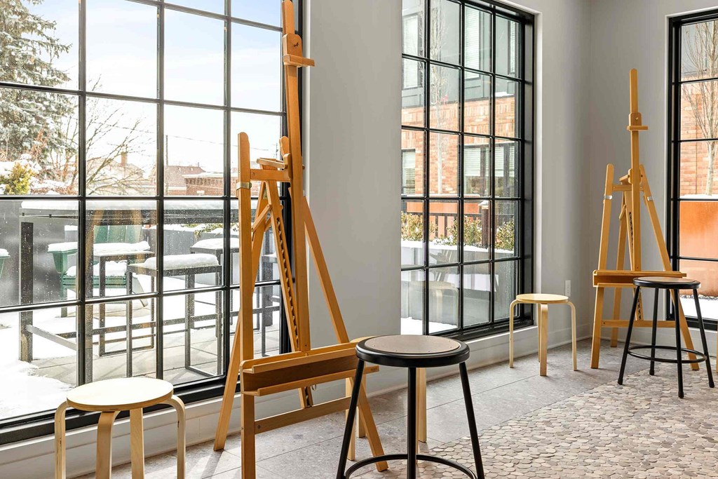 Two wooden easels stand in a room with a large window.
