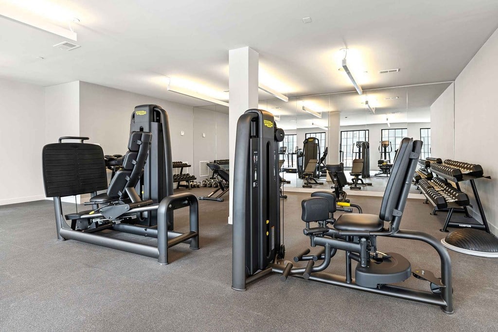 A gym with a variety of equipment including a leg press machine and a seated calf raise machine.