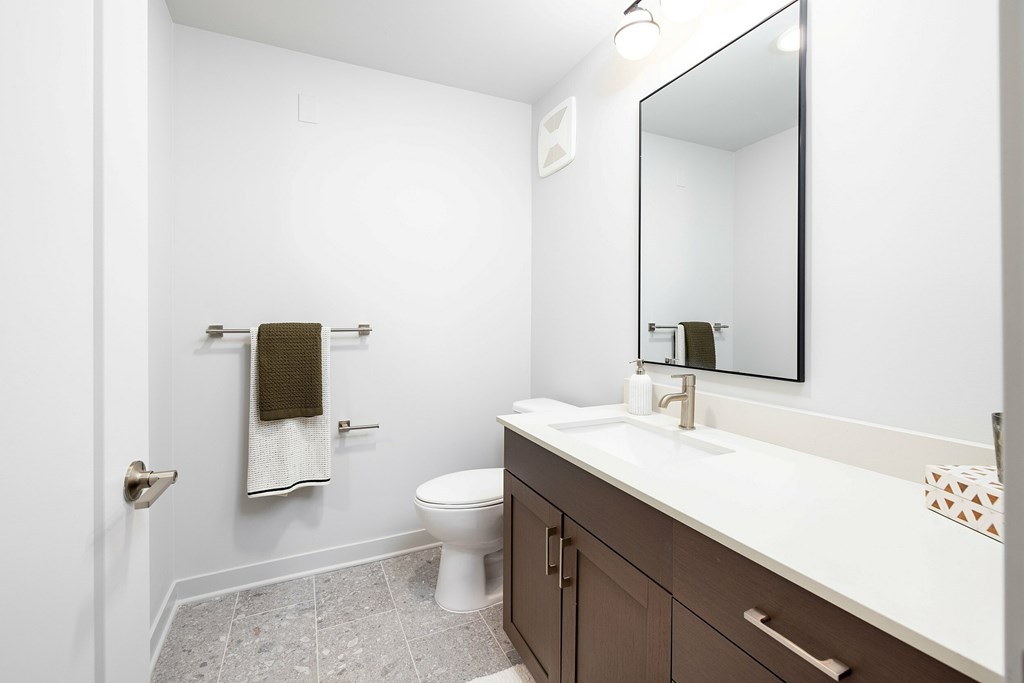 A bathroom with a toilet, sink, and mirror.