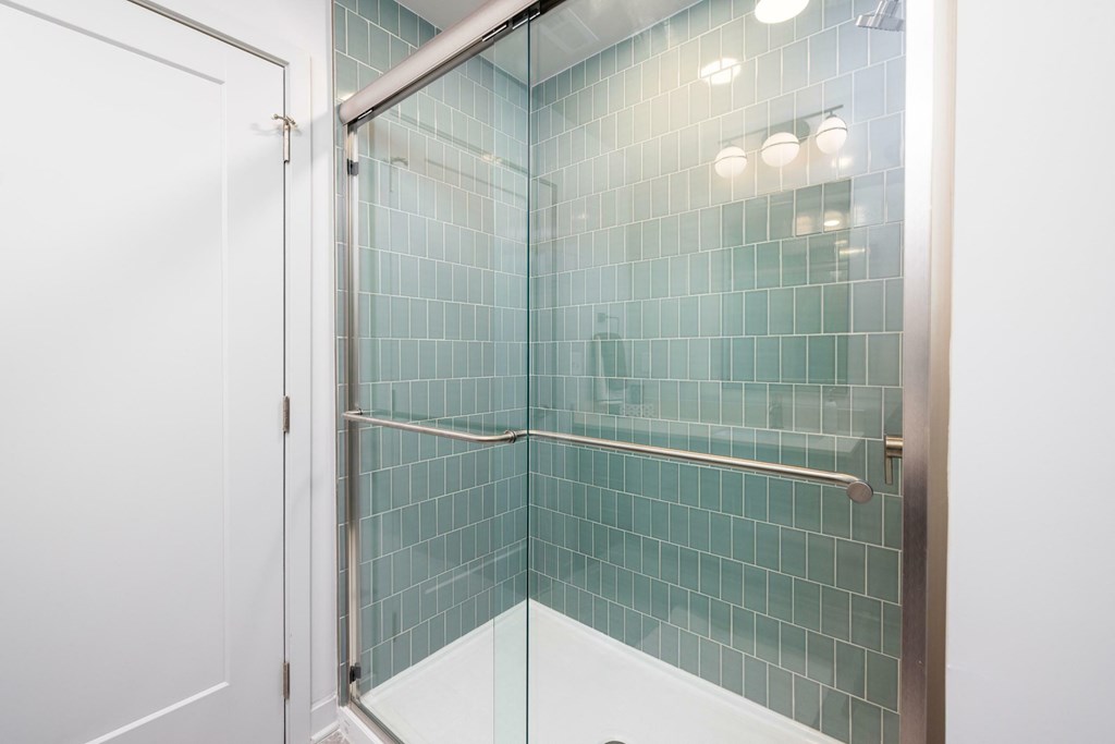 A white door is open to a shower with a glass door.
