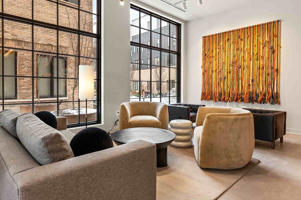 A modern living room with a large window and a wooden wall art.