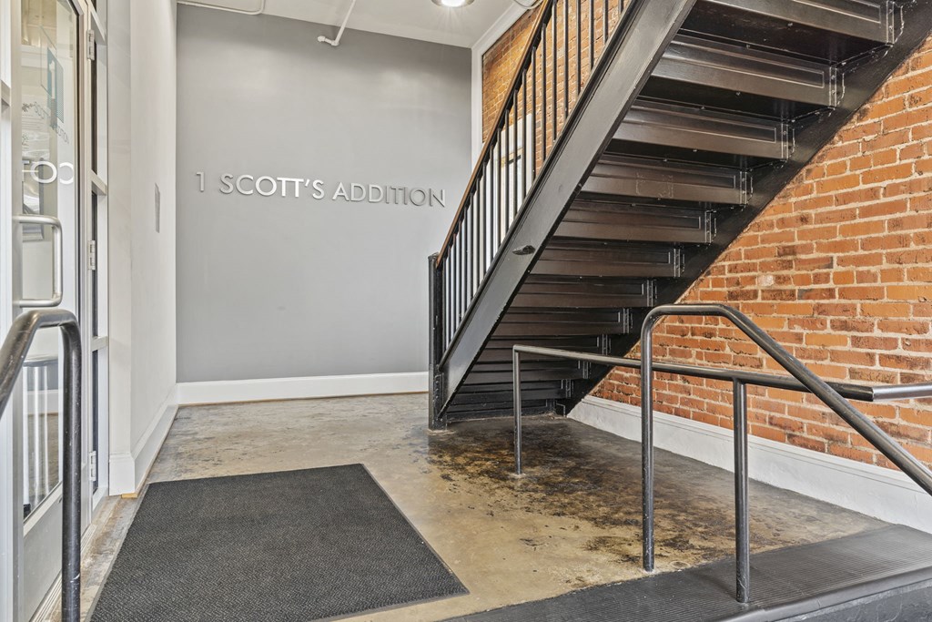 the lobby of a building with a staircase and a brick wall