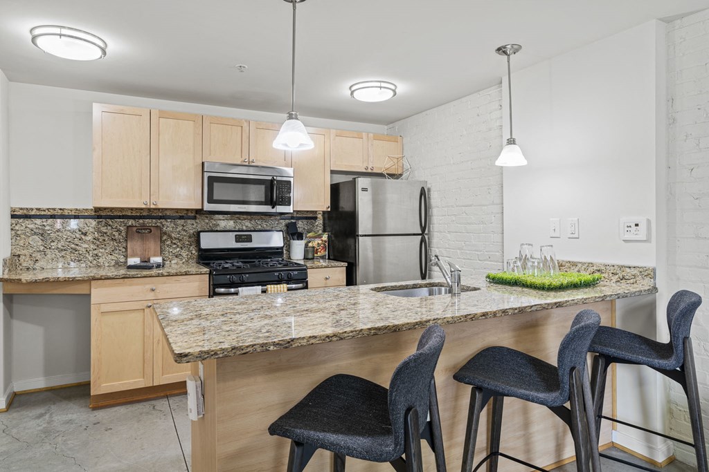 a kitchen with a marble counter top with three chairs