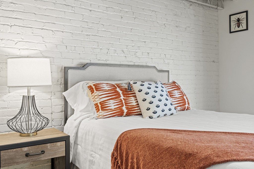 a bedroom with white brick walls and a bed with pillows