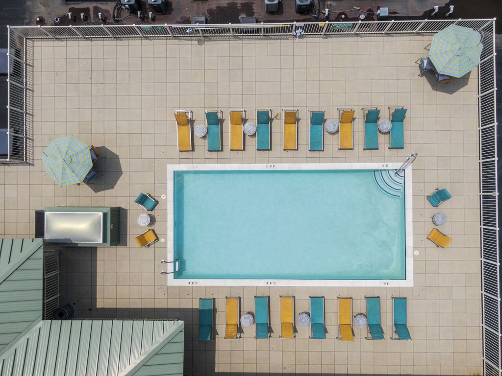 an overhead view of a swimming pool with pool chairs and a television