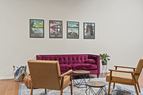 a living room with a couch and chairs and posters on the wall