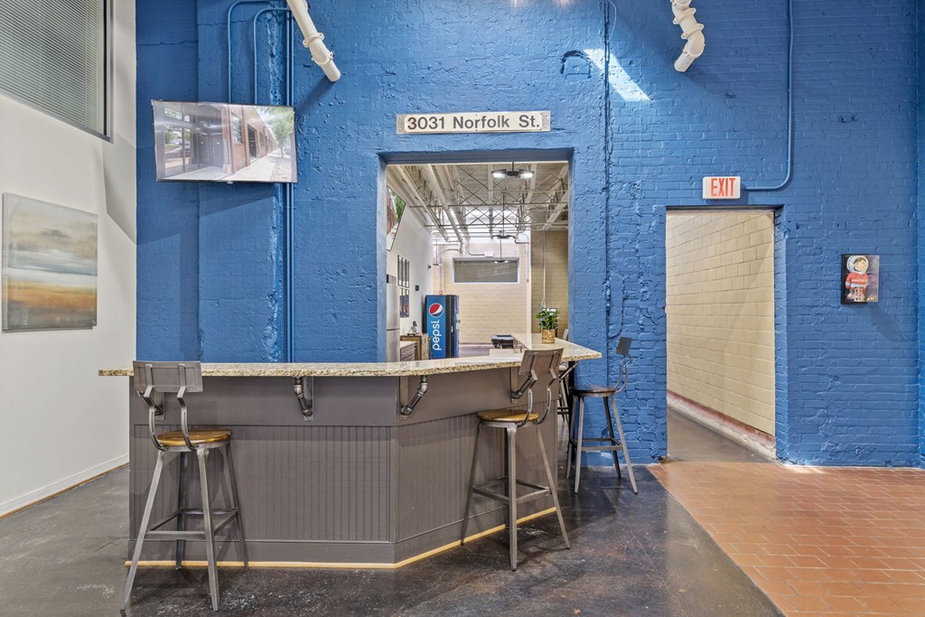 a bar in the corner of a blue building with stools