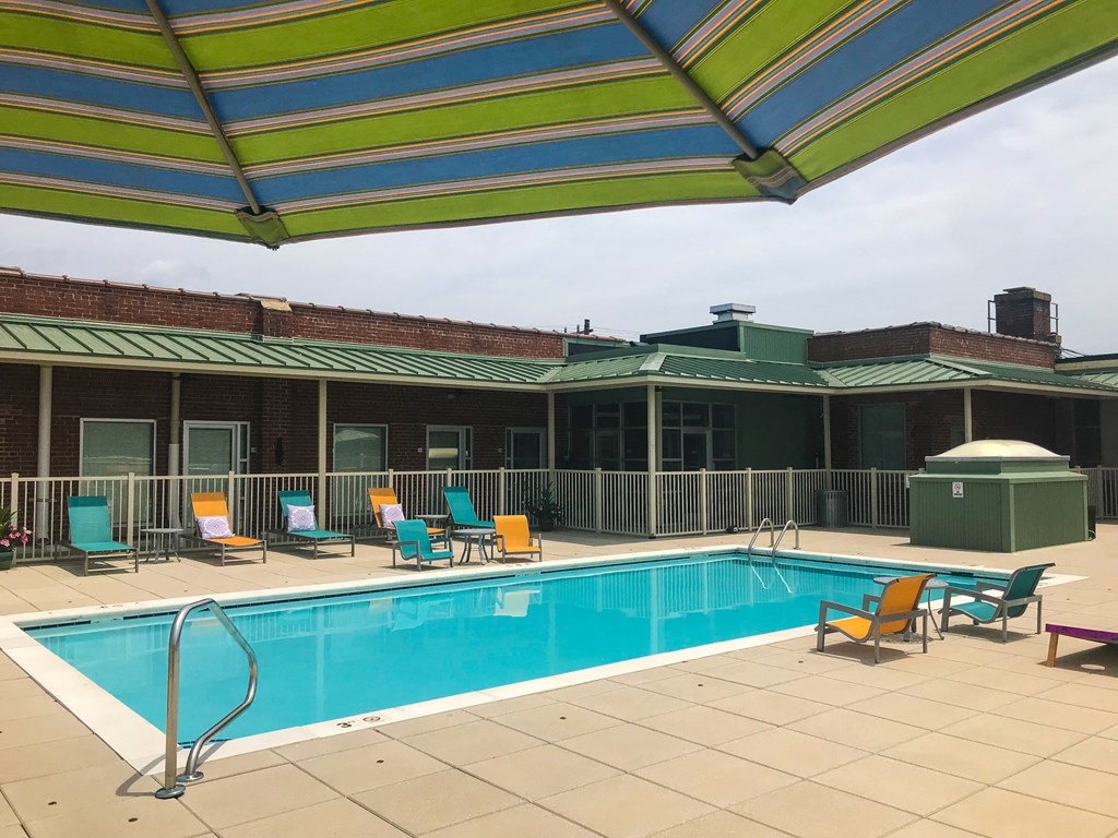 a swimming pool with chairs and an umbrella next to a hotel pool