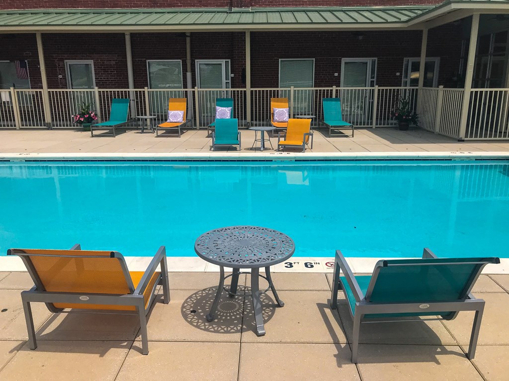 a swimming pool with a patio with chairs and a table