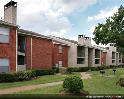 an apartment building with a green yard in front of it
